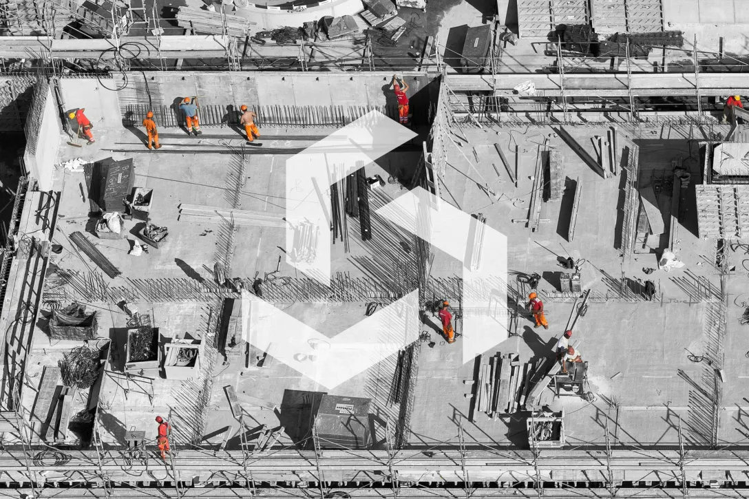 Luftaufnahme einer Baustelle mit Arbeitern in Sicherheitskleidung auf Betondecke – Rohbau mit Bewehrungsstahl für Betonkonstruktion