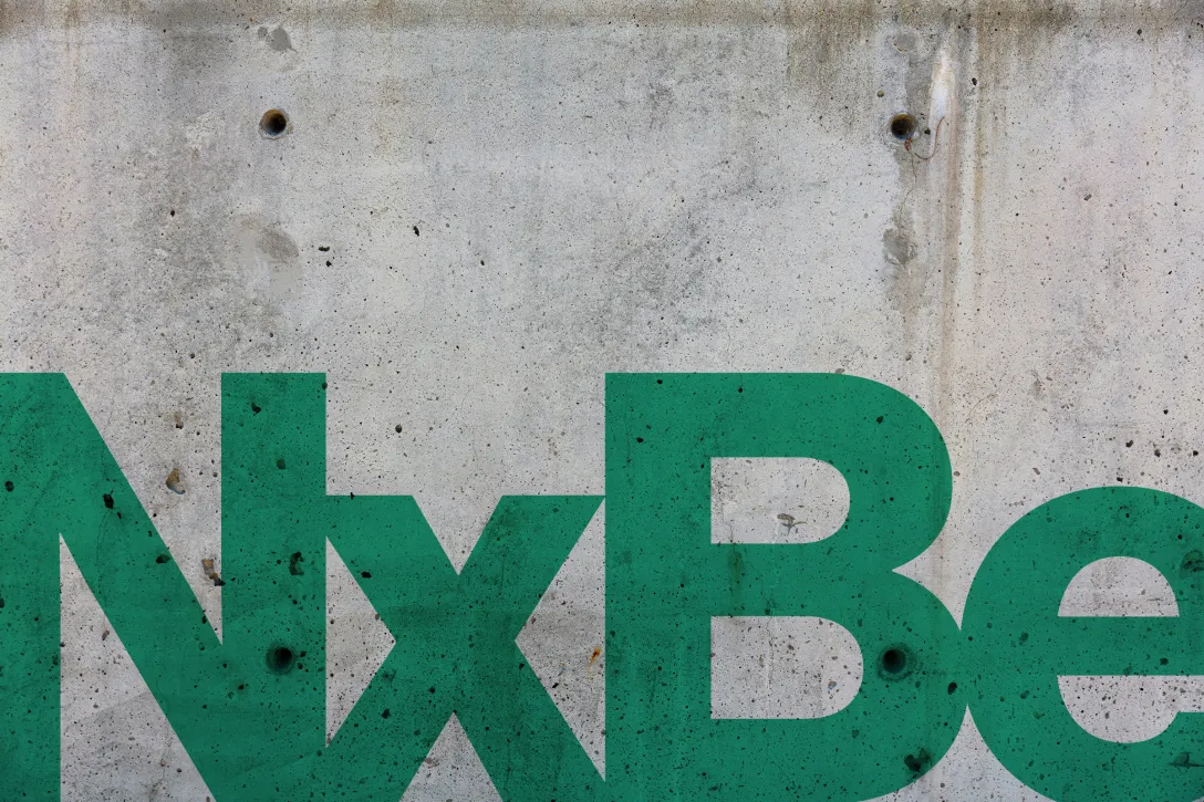 NxBee-Schriftzug in Jungle Green auf Betonwand – markantes Hexagon-Symbol aus der Wabengeometrie integriert in die Wortmarke